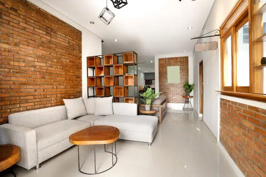 Modern industrial farmhouse living room interior with brick walls, sofa, coffee table and shelves
