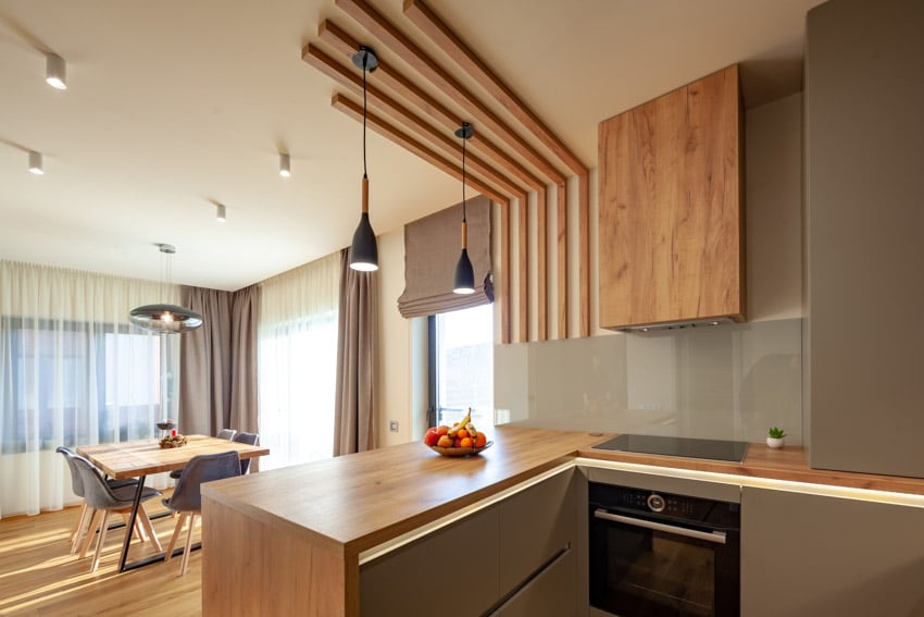 Modern kitchen with teak countertop, pendant lights, and dining space