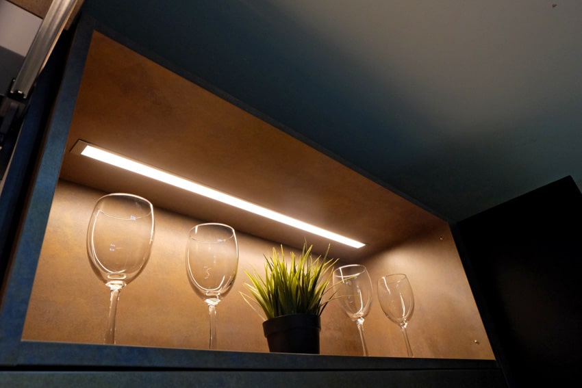 Modern kitchen with wallpaper inside cabinet, lighting fixture, and wine glasses