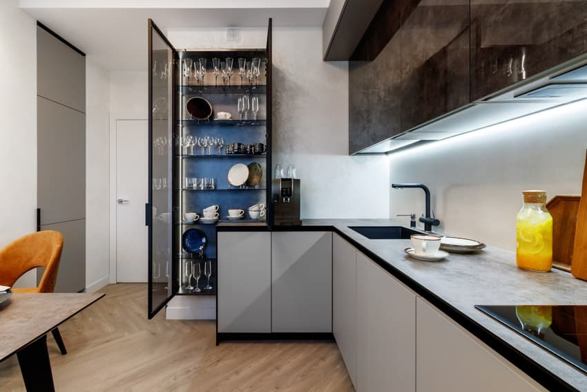 Modern kitchen with wallpaper inside glass cabinet, countertop, backsplash, faucet, sink under cabinet, lighting, and wood flooring