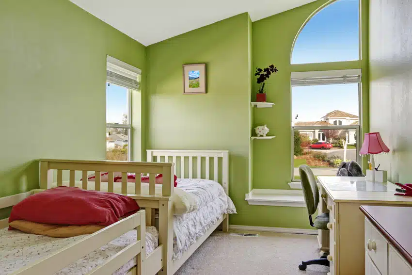 Bedroom with home office, green walls, comforter, desk, chair, floating corner shelves, and windows