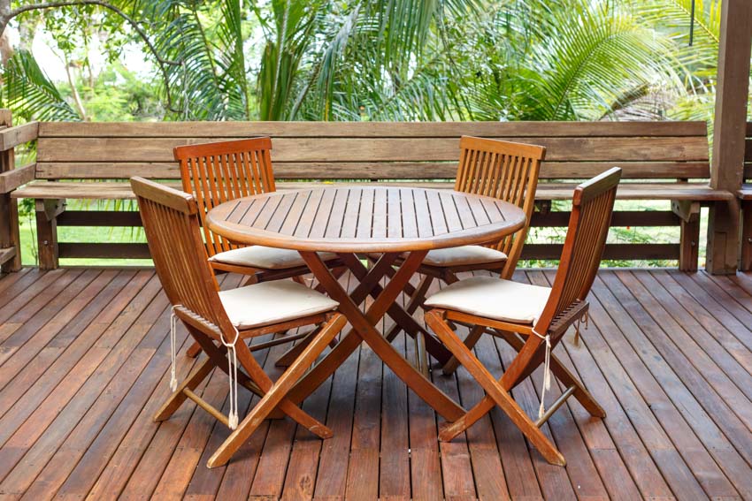 Outdoor patio with teak wood table, chairs, and wood plank flooring