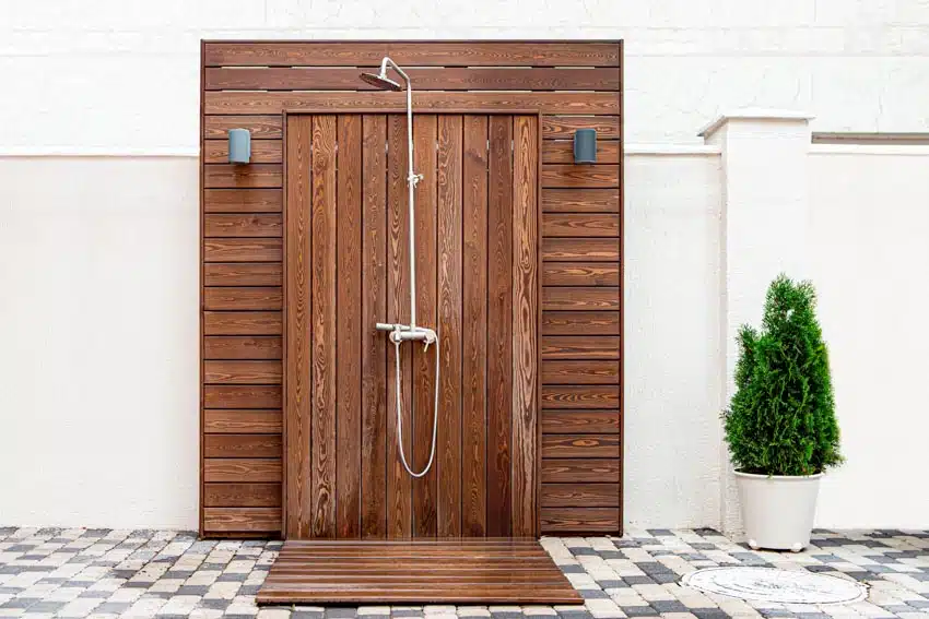 Outdoor shower with waterproof shiplap, showerhead, tile flooring, and potted plant