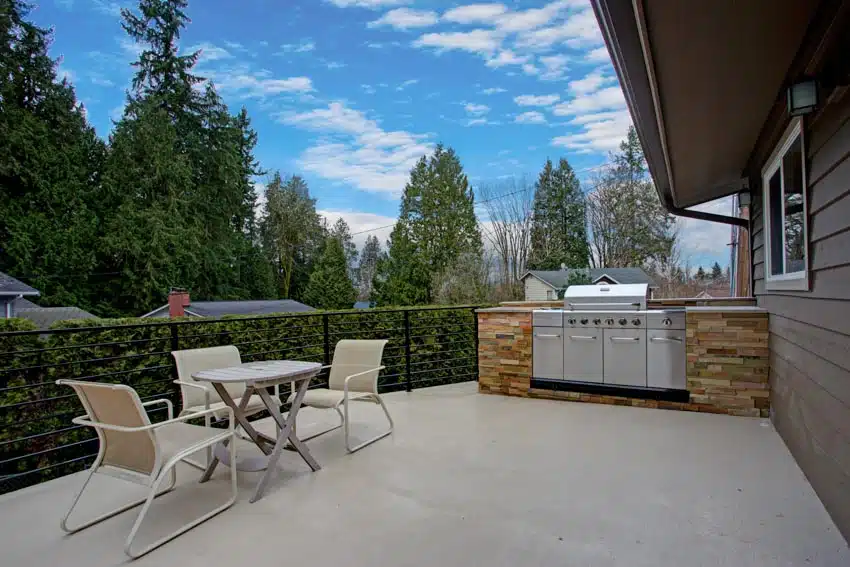 Painted concrete patio with outdoor kitchen with a dining table with three seats