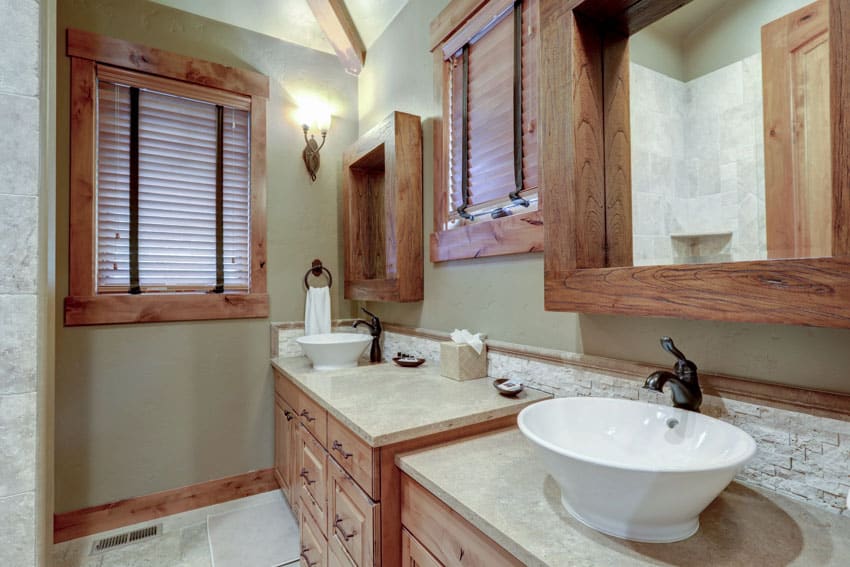 Rustic light green bathroom with wood drawers, vanity mirrors, sinks, faucets, countertops, and window blinds