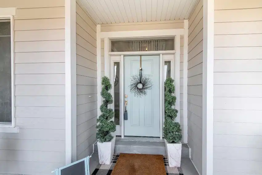 Sage green front door with transom window and two side panels in gray painted house exterior
