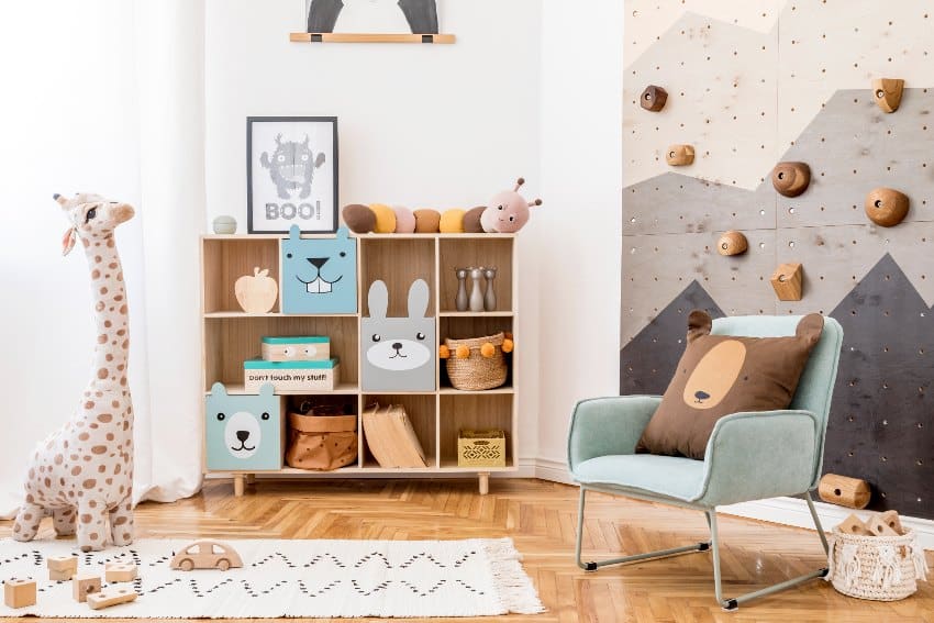 Scandinavian interior design of playroom with modern climbing wall for kids, designed furniture, mint armchair, organized soft toys, teddy bear and cute children's accessories