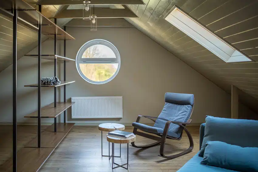 Small attic living room with shelves, rocking chair, ceiling lights, and windows