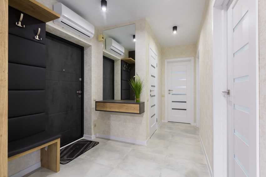 Small hallway with downlight, split type air conditioner, mirror tile floors, and white doors