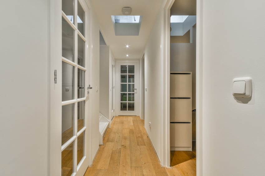 Small hallway with glass doors, wood floors, and ceiling lighting fixtures