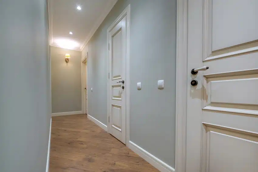 Small hallway with light blue walls, doors, wood floors, and wall sconce