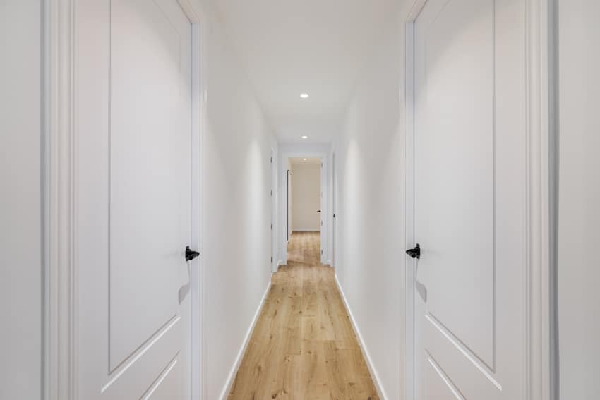 Small hallway with white walls, wood floors, and ceiling lights