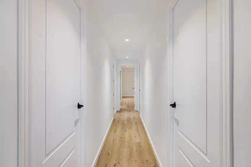 Small hallway with white walls, wood floors, and ceiling lights