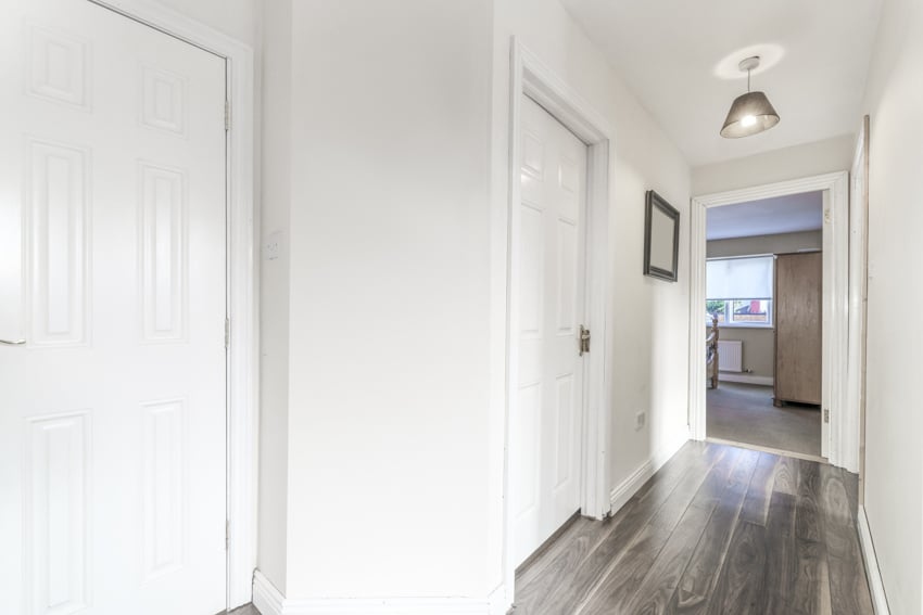 Small hallway with white walls, wood laminate flooring, and pendant light