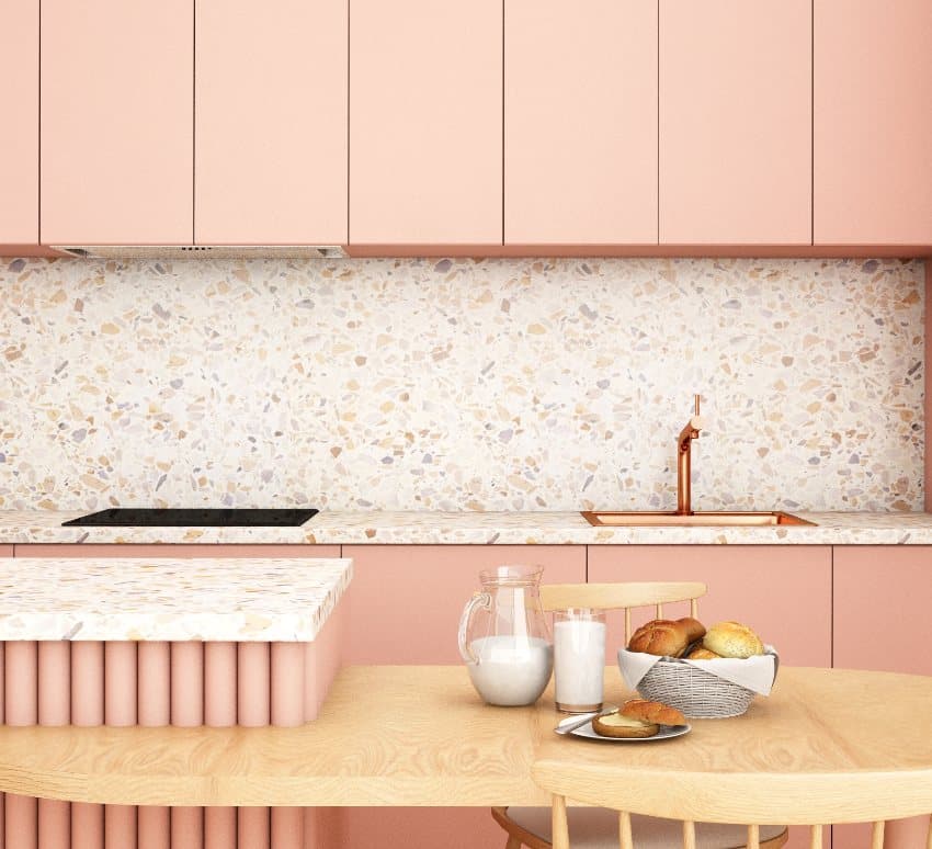 Warm and peach tone kitchen interior with wooden table and chairs, copper faucet and terrazzo countertop