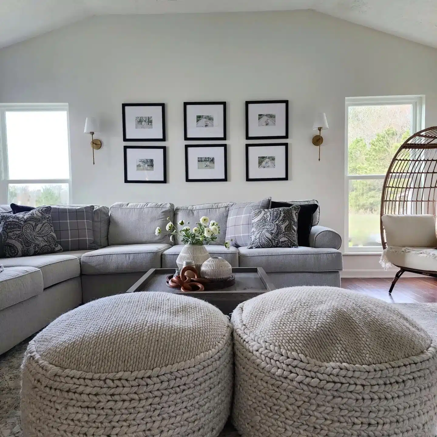 Living room with large sectional, wicker egg chair and knitted poufs