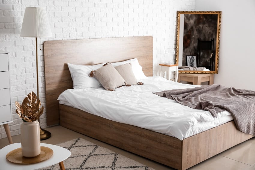 Bedroom with American walnut wood bed, mattress, floor lamp, and white brick wall