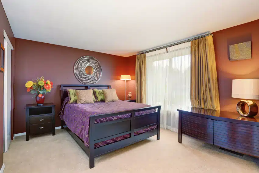 Bedroom with nightstands, lamp, window, dark purple walls, and curtains