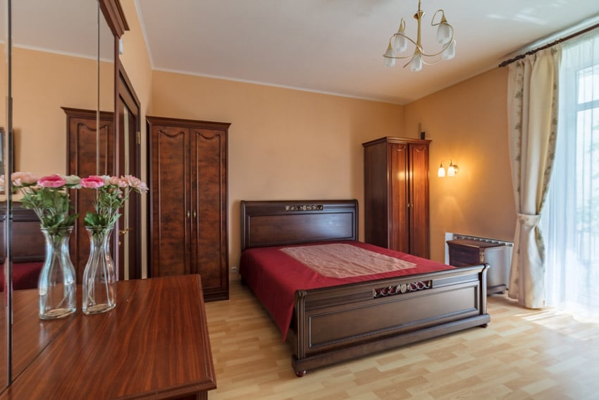 Bedroom with dark walnut wood wardrobe, mattress, wood floor, and curtain