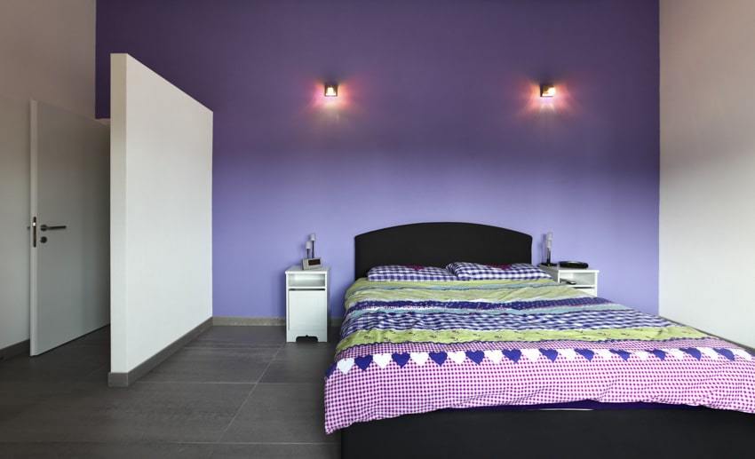 Bedroom with purple walls, nightstands, and wall sconces
