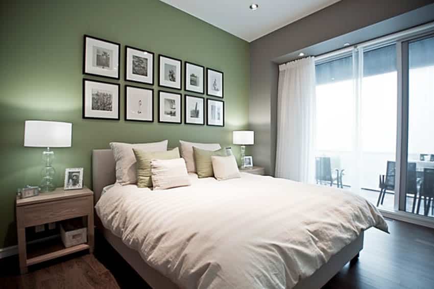 Bedroom with sage green accent wall, bedding, pillows, nightstands, lamps, and glass door
