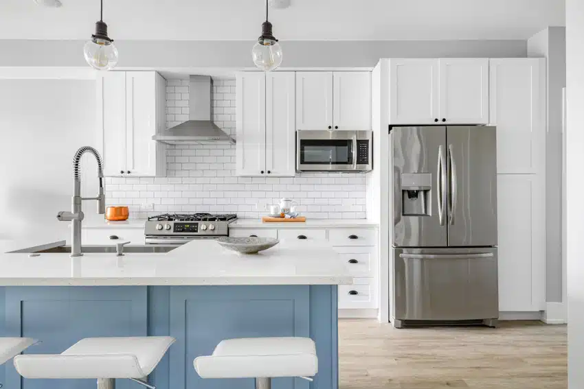 Kitchen with blue island, white countertops, tile backsplash, cabinets, pendant lights, refrigerator, and wood floors