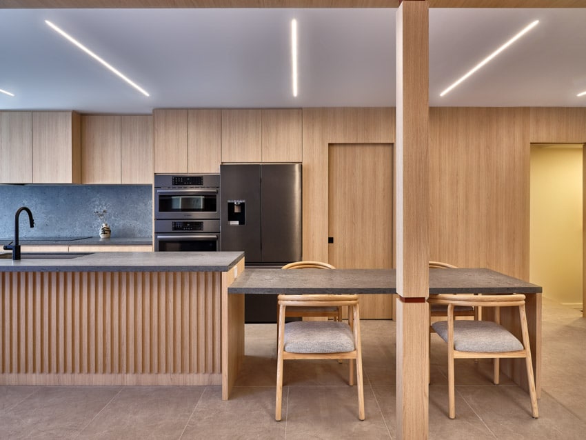 Harty house kitchen with wood slat island, appliances, and dining area