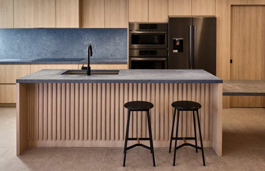 Harty house kitchen with wood slat island, countertop, backsplash, and bar stools