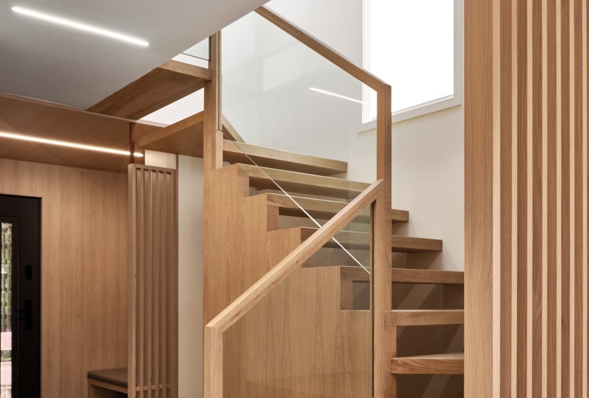 Harty house interior with wood slat divider, glass panels, and floating staircase