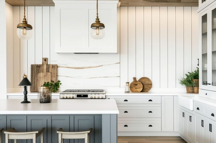Kitchen with shiplap backsplash, dark gray island, and white cabinets