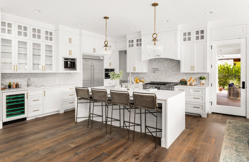 Kitchen with marble backsplash, island,cabinets, and high backed chairs