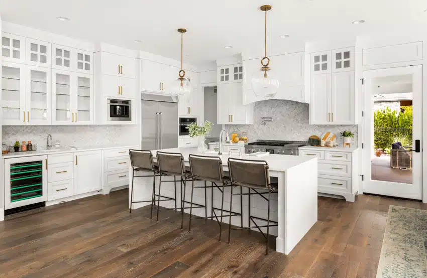 Kitchen with marble backsplash, island,cabinets, and high backed chairs