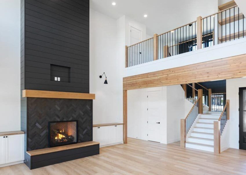 Farmhouse living space with fireplace, black shiplap accent wall, and staircase