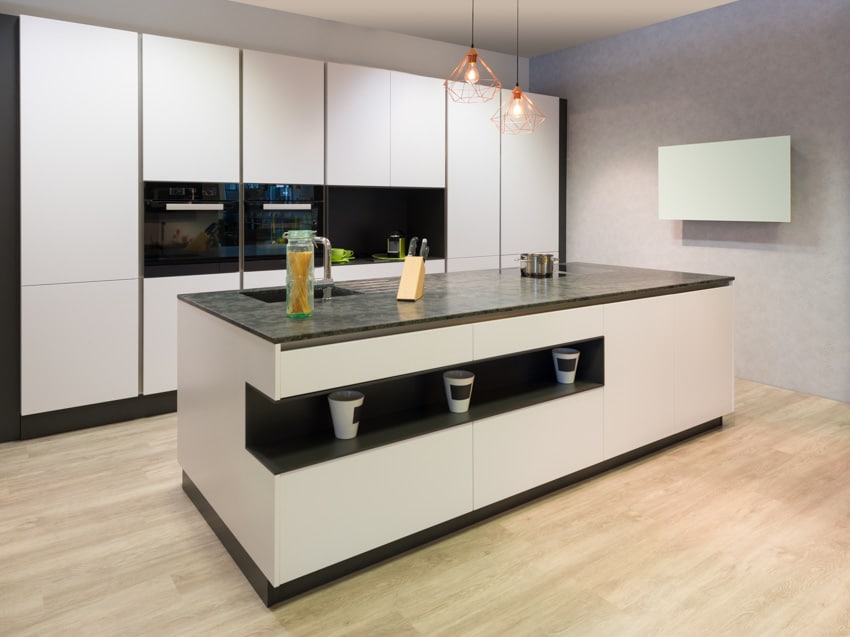 Modern kitchen with white cabinets, black backsplash, countertops, pendant lights, and kitchen island with storage options