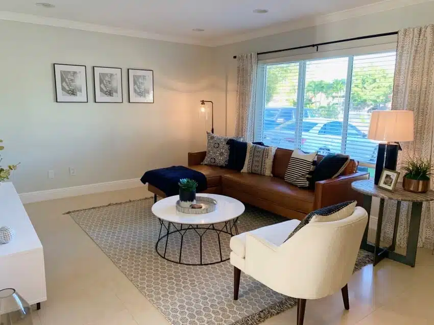 Living room with sofa, armchair, floor lamp, coffee table, rug, and window