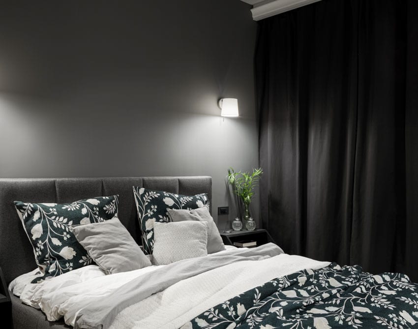 Basement bedroom with comforter, wall-mounted lights, and drapery panel