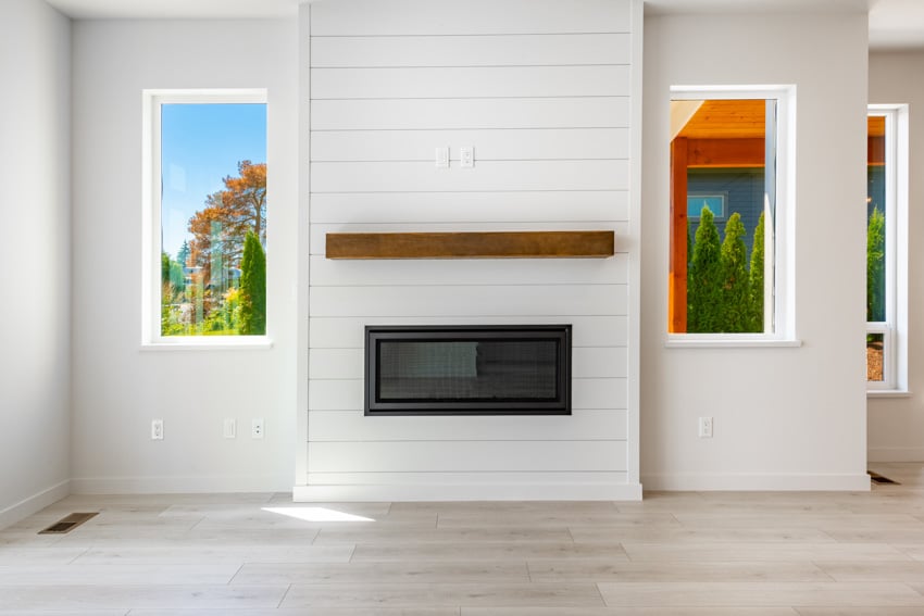 Empty farmhouse room with shiplap horizontal board fireplace with stained mantel