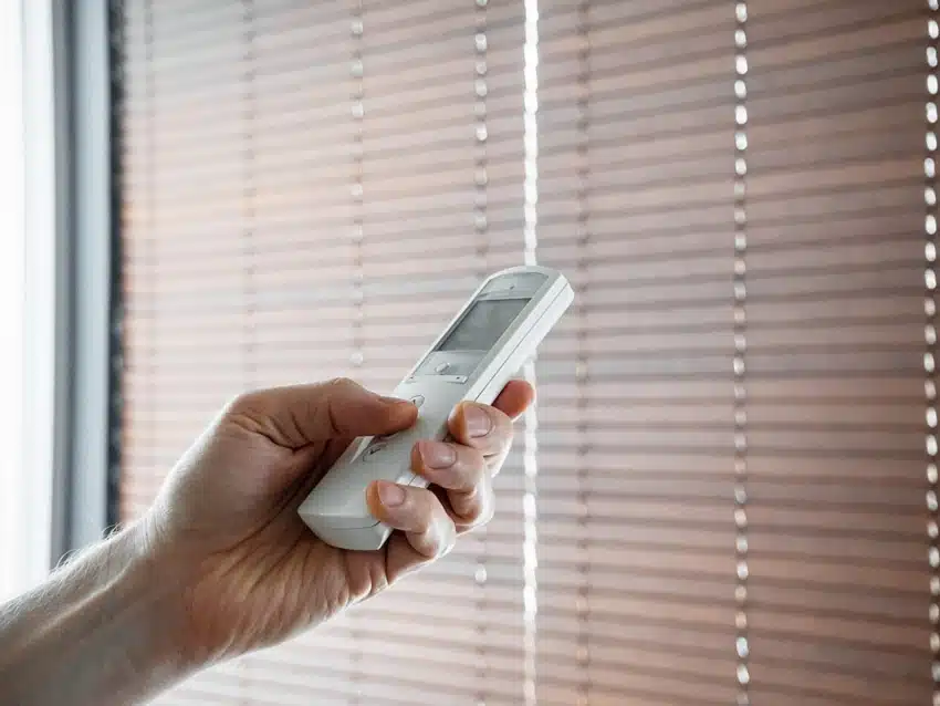 Individual holding a remote to control motorized blinds 