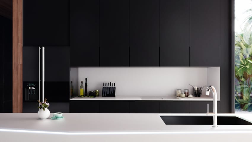 Minimalist kitchen with black cupboards, and white quartz surfaces