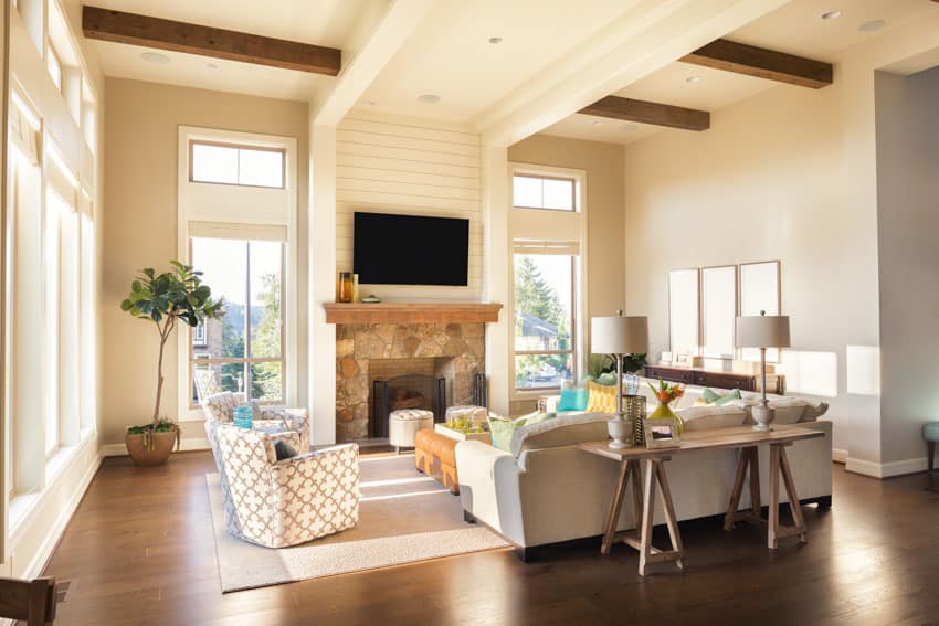 Room with TV on the fireplace, armchairs, and wood flooring