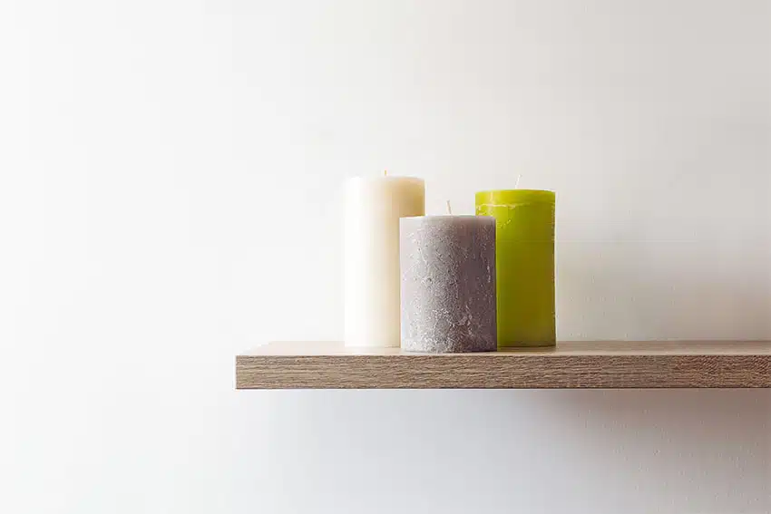 Different sizes of pillar candles on floating shelf