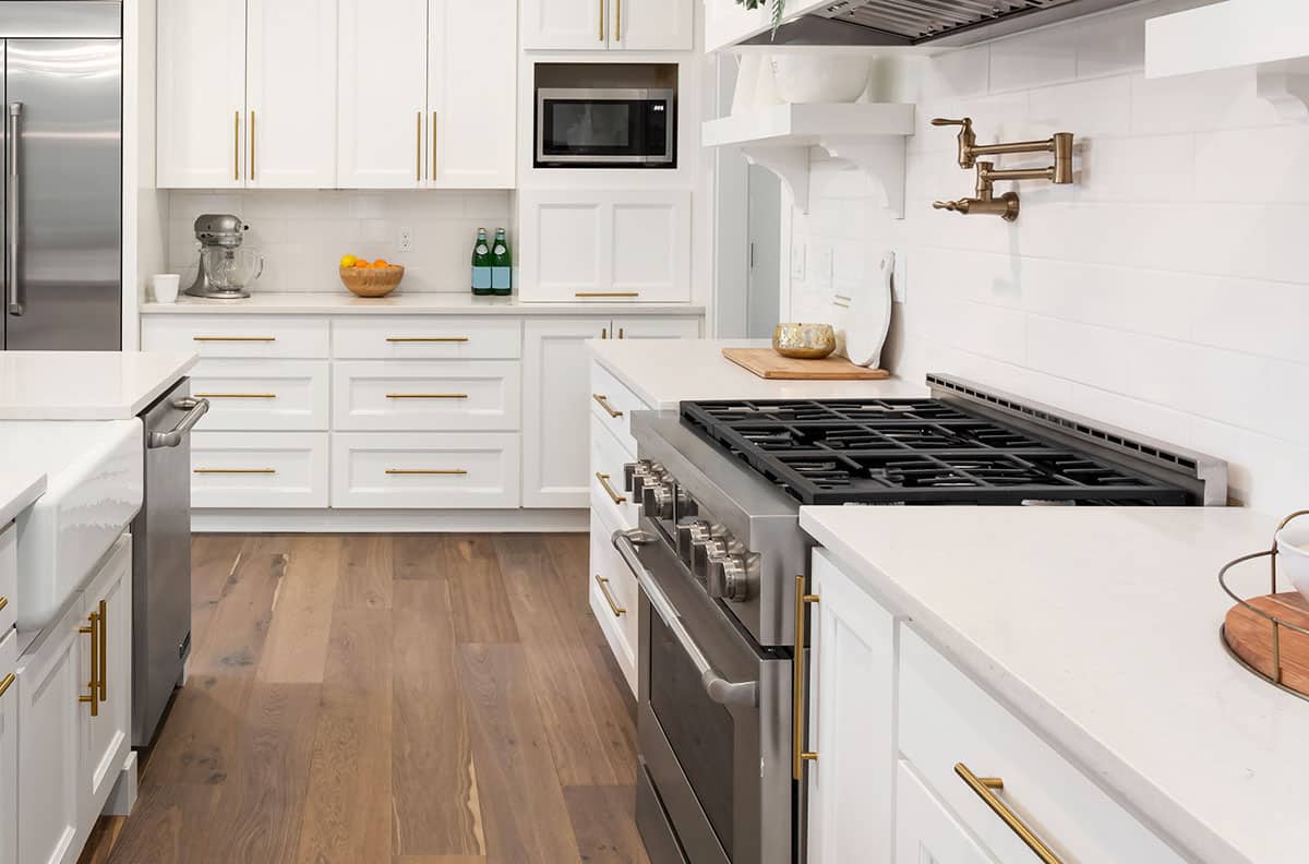 Contemporary kitchen with wood flooring white cabinets subway backsplash