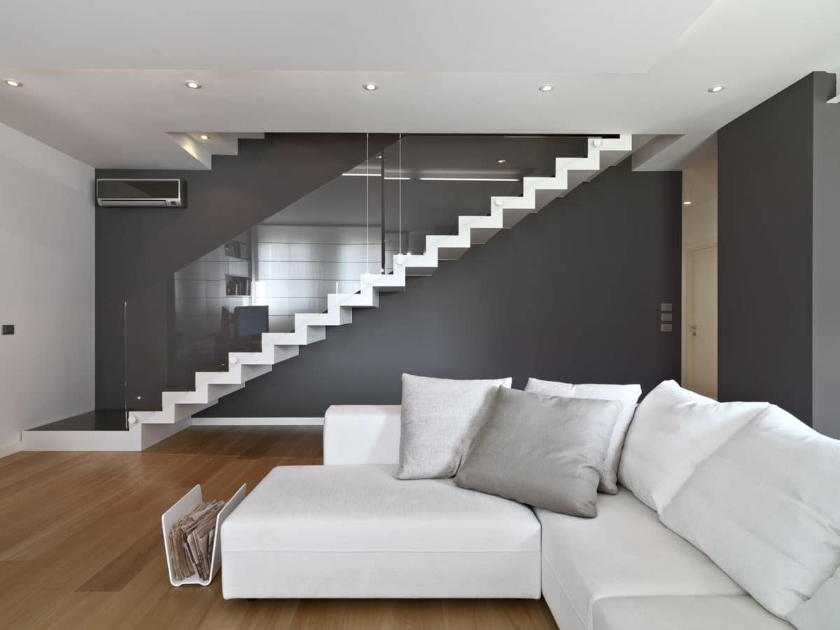 basement room with white sofa staircase and wood floor