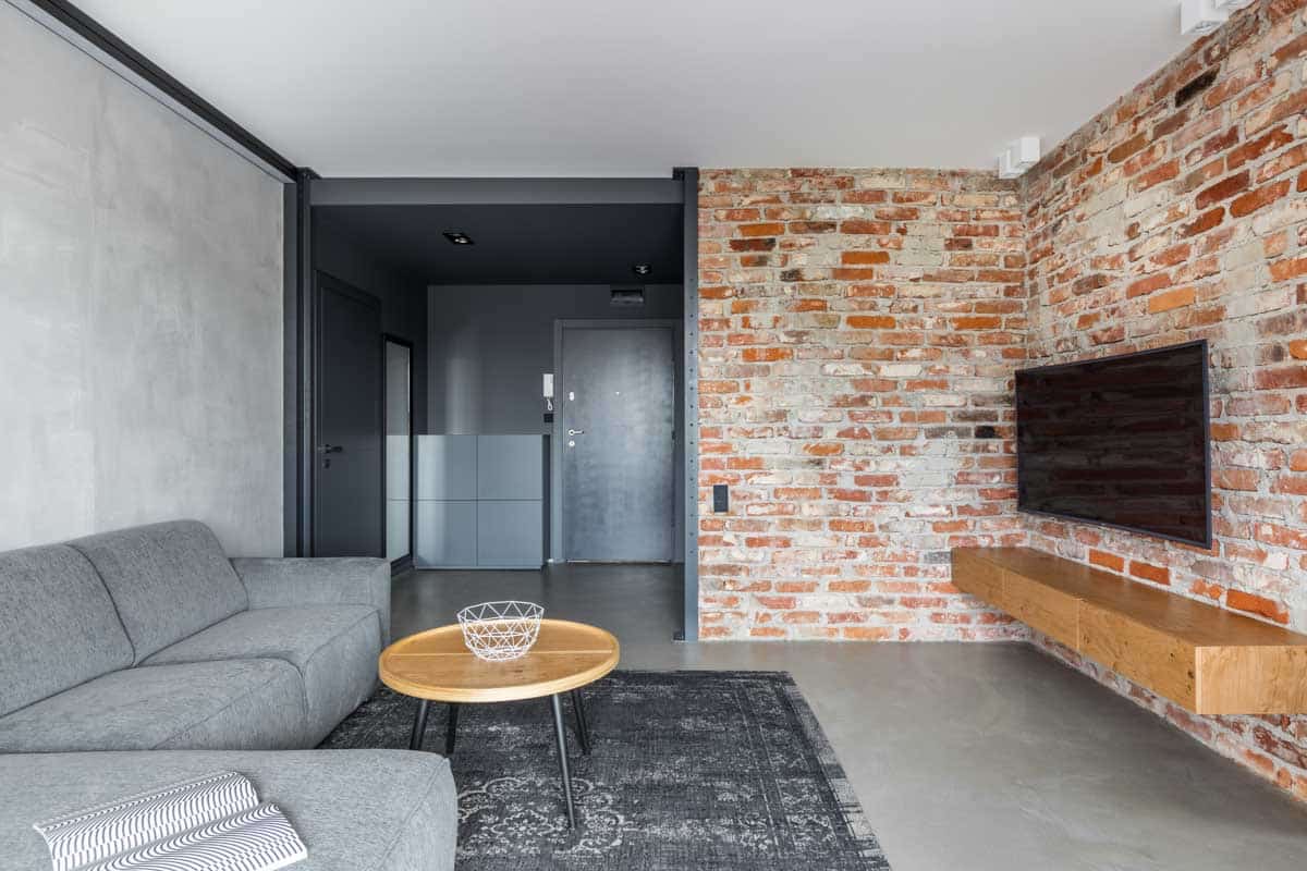 basement with brick wall, tv, rug and sofa