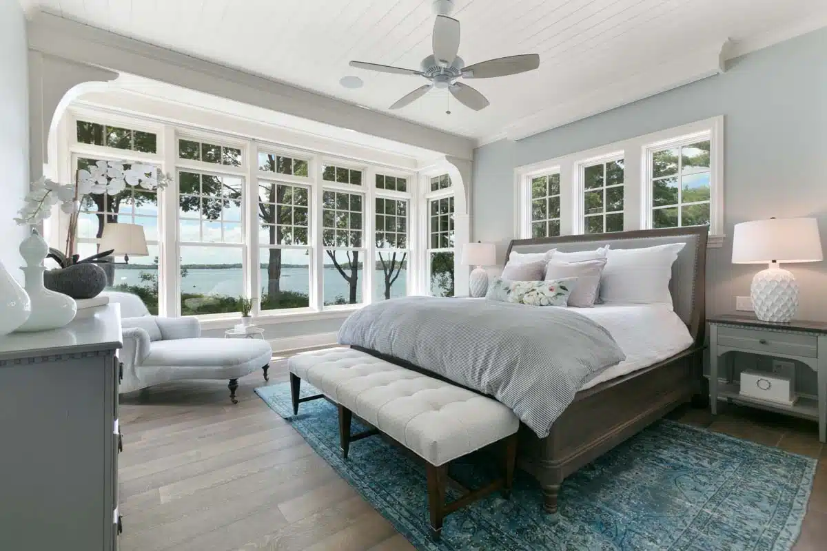 coastal bedroom with chair ceiling fan and windows