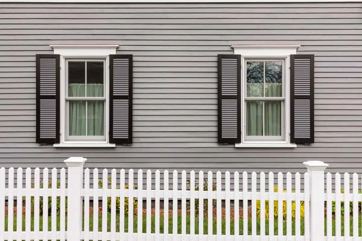 gray house siding with windows and fencing