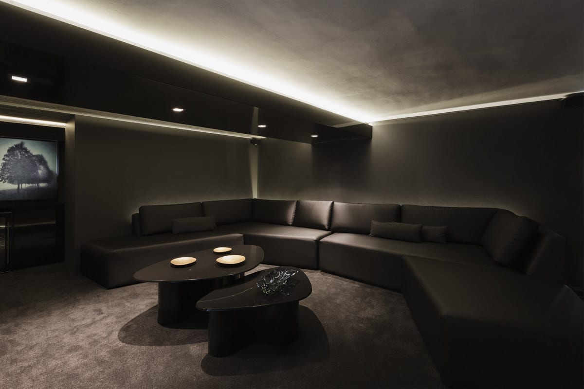 home cinema with black colored walls sofa and tv