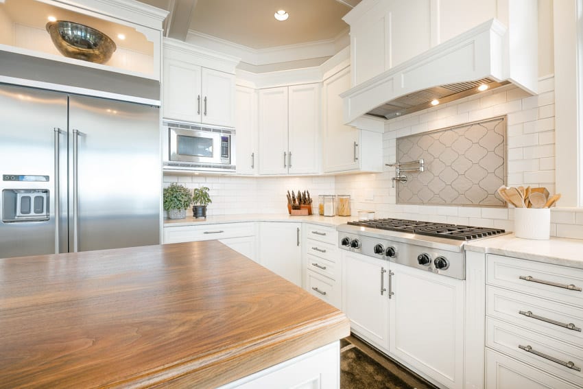 kitchen with two tone backsplash, bright cabinets and wood surfaces