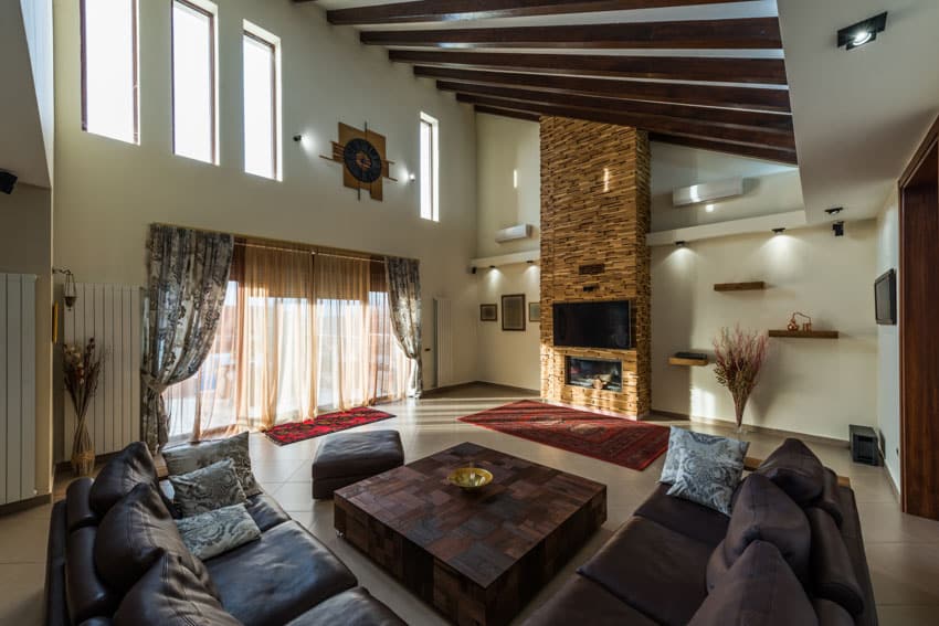rustic room with high ceiling fireplace and sectional sofa