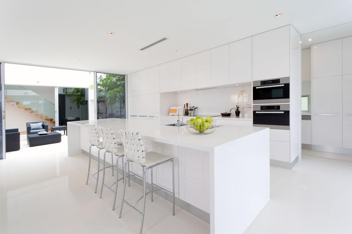 spacious kitchen with island stools and backsplash made of corian